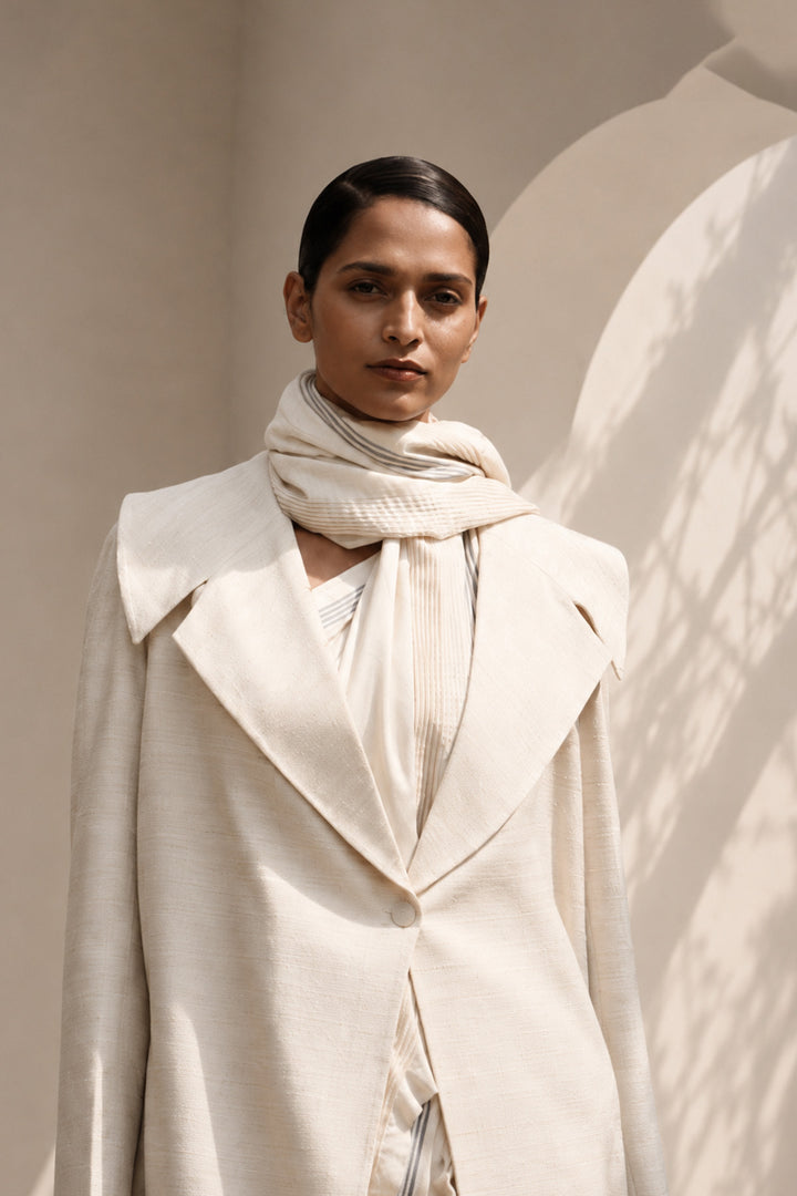 Ivory ensemble featuring oversized lapel collar, structured fit and fluid drape.