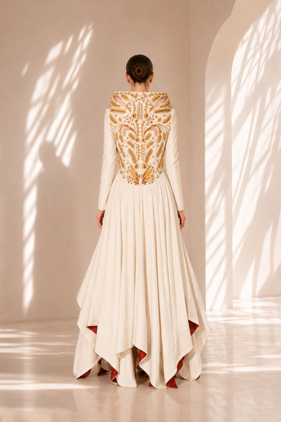 Ivory high-low gown enriched with regal gold embroidery and dramatic layered drapes