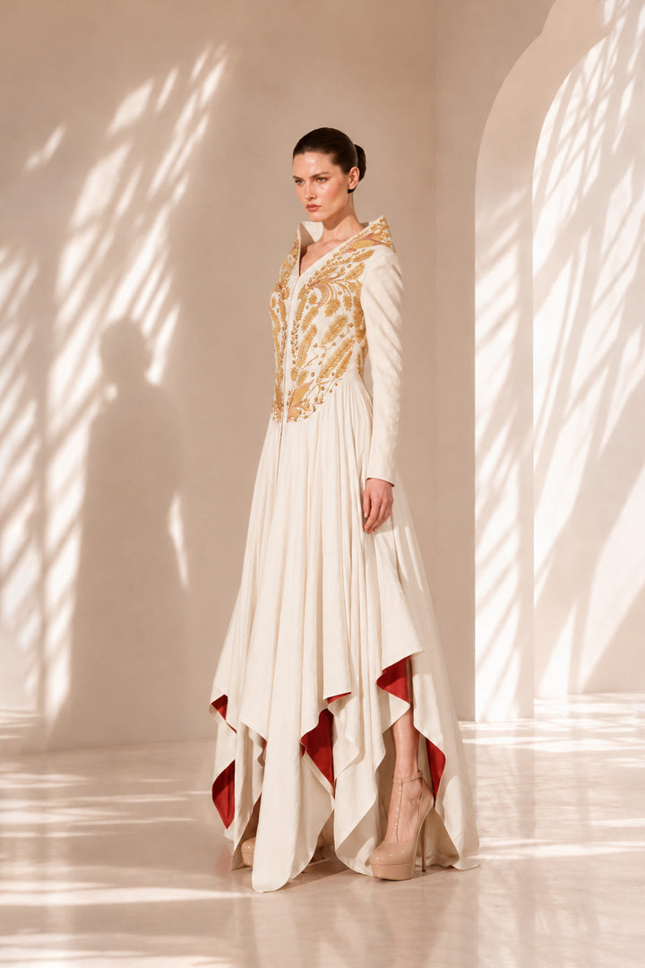 Ivory high-low gown enriched with regal gold embroidery and dramatic layered drapes