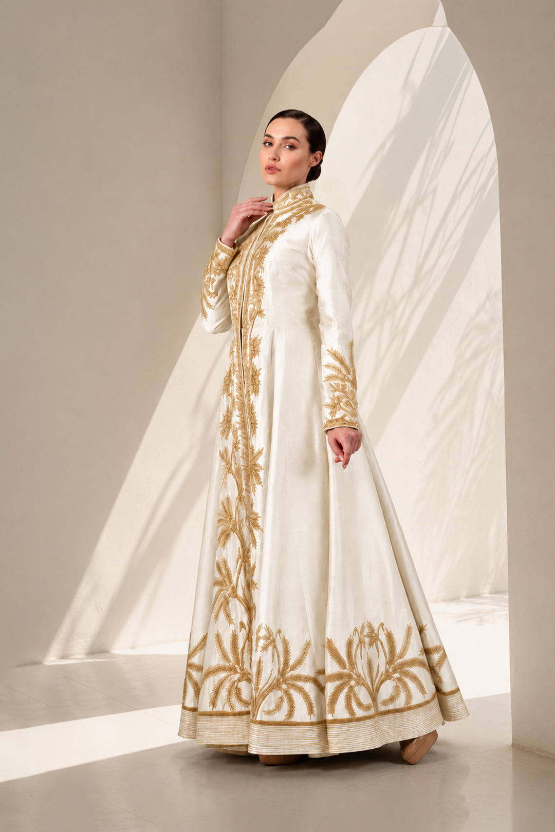 Ivory floor-length gown adorned with full-length sleeves and intricate gold-toned palm-inspired embroidery.