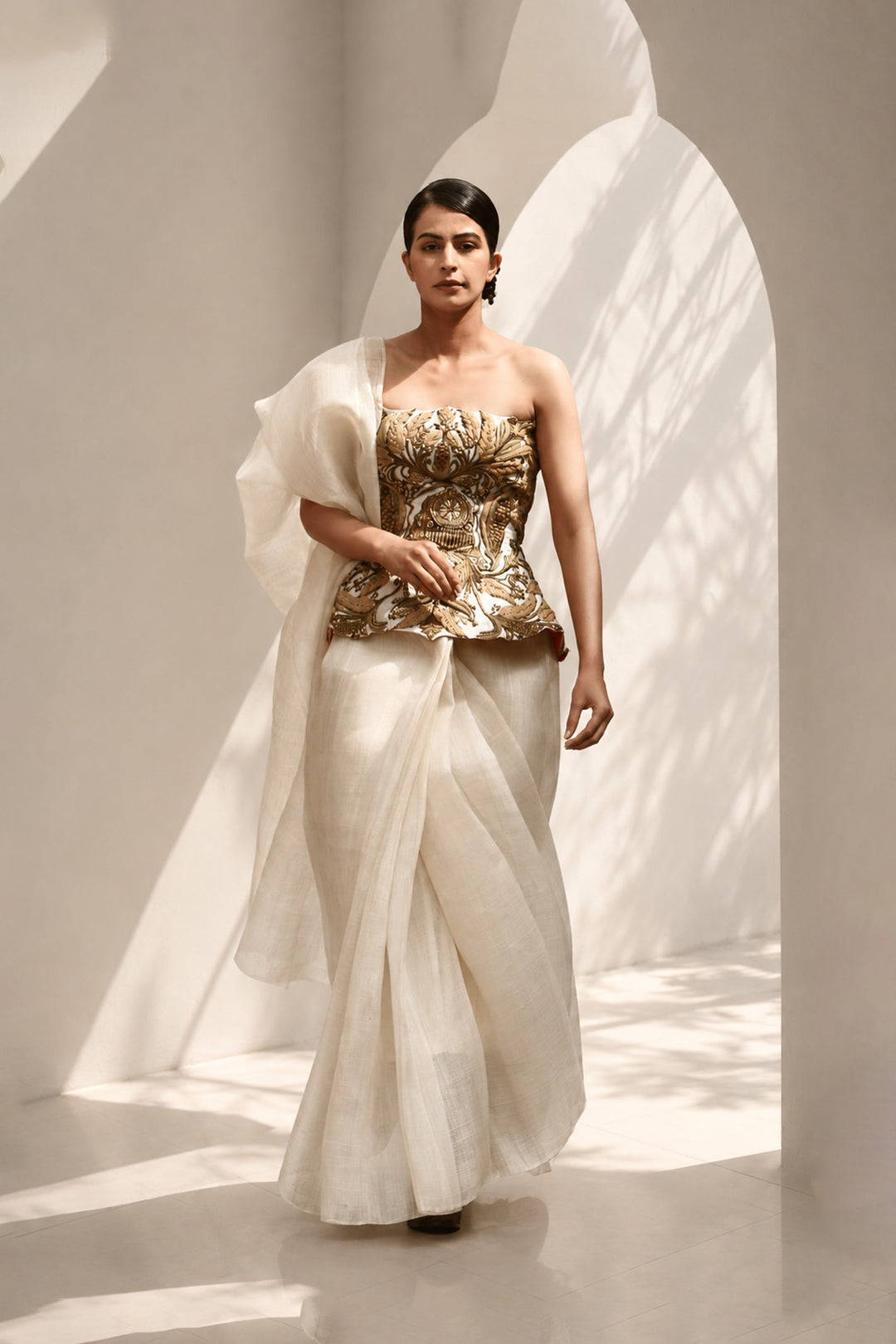 Ivory ensemble featuring structured embroidered peplum bodice, and sheer flowing draped saree.