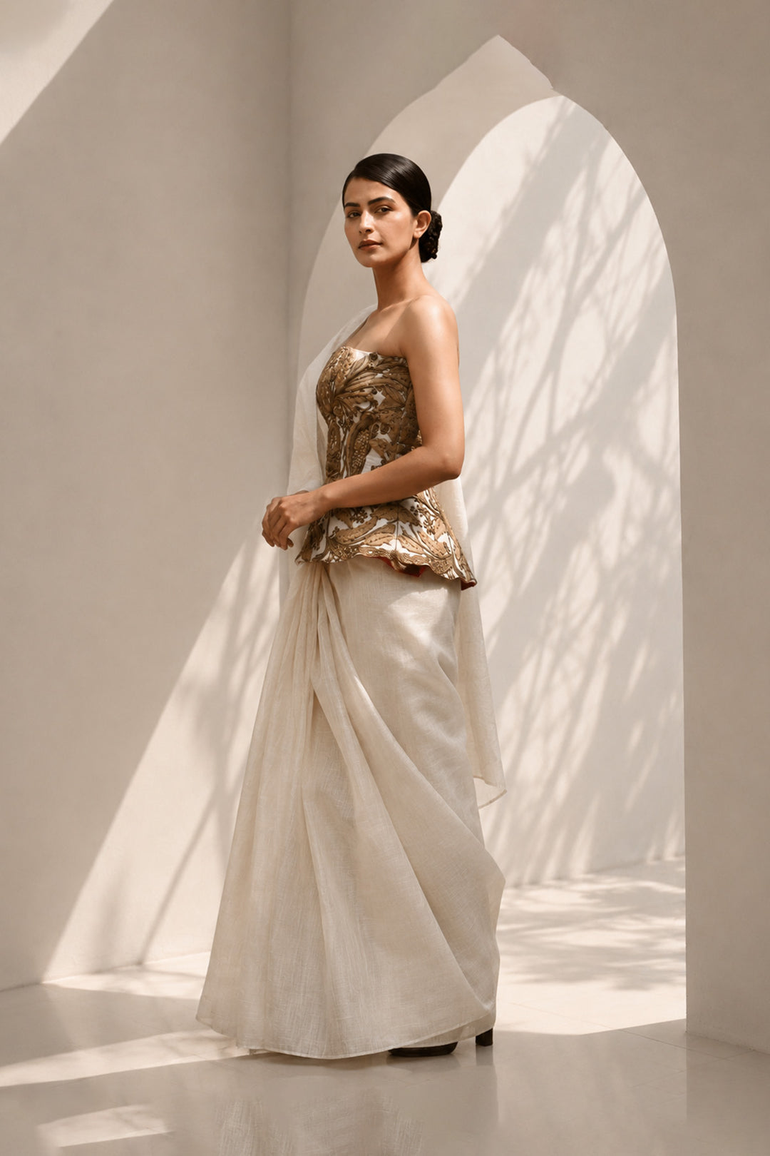 Ivory ensemble featuring structured embroidered peplum bodice, and sheer flowing draped saree.