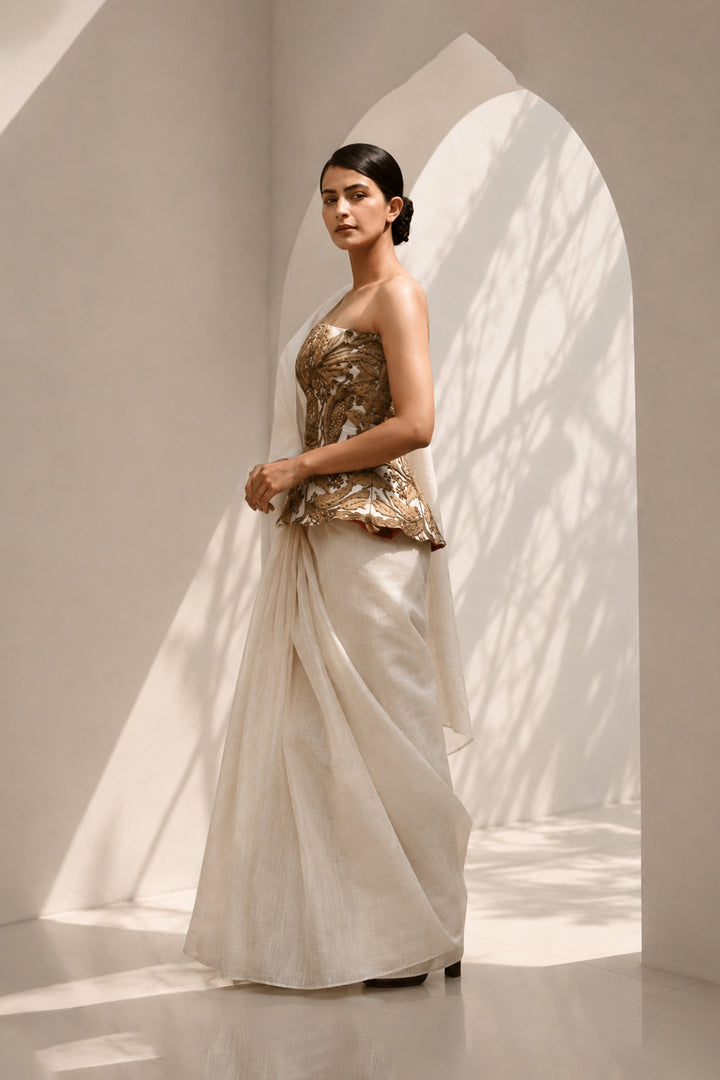 Ivory ensemble featuring structured embroidered peplum bodice, and sheer flowing draped saree.