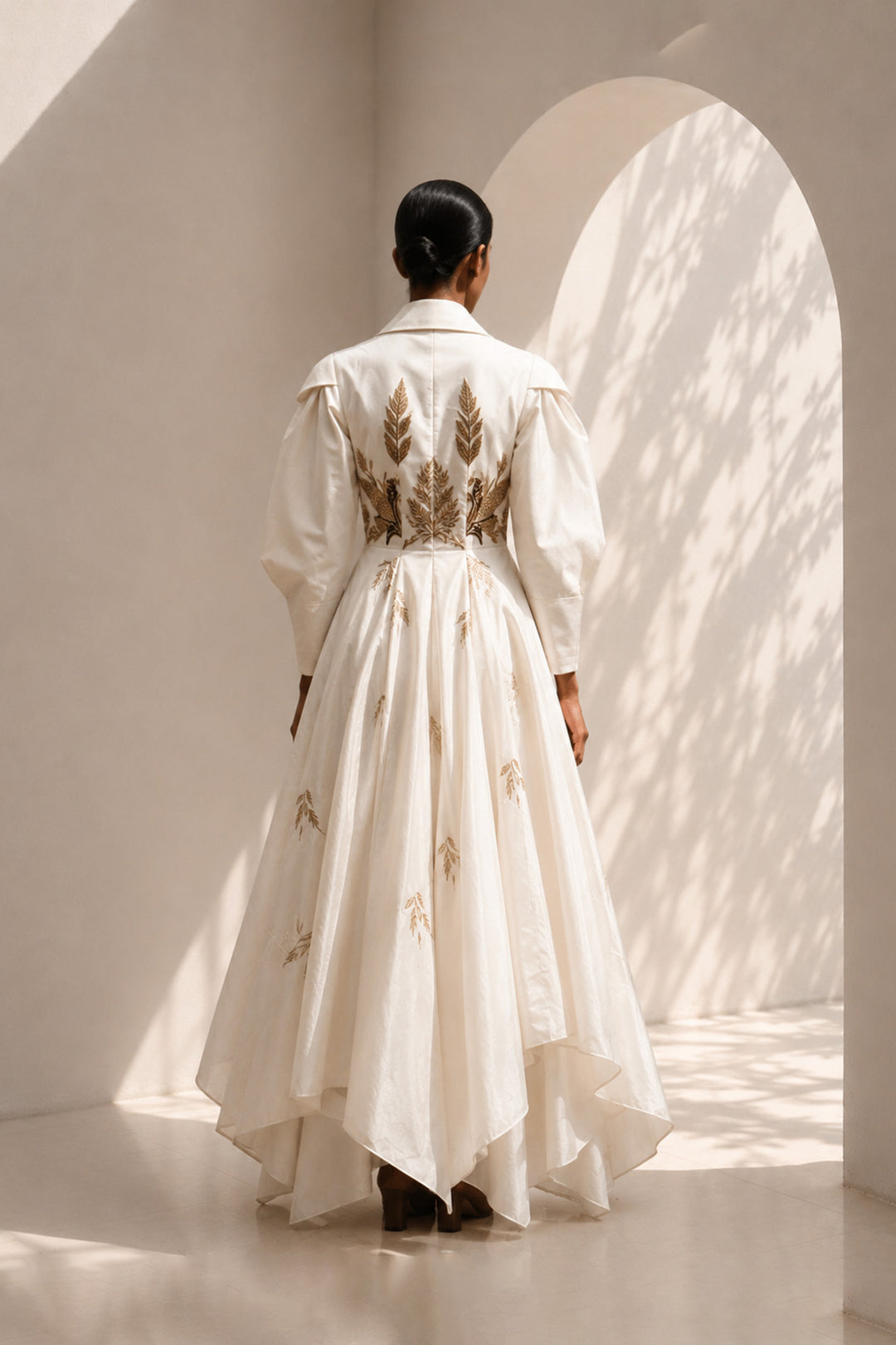 Ivory statement gown featuring sculptural sleeves, delicate embroidery, and an effortlessly flowing silhouette.