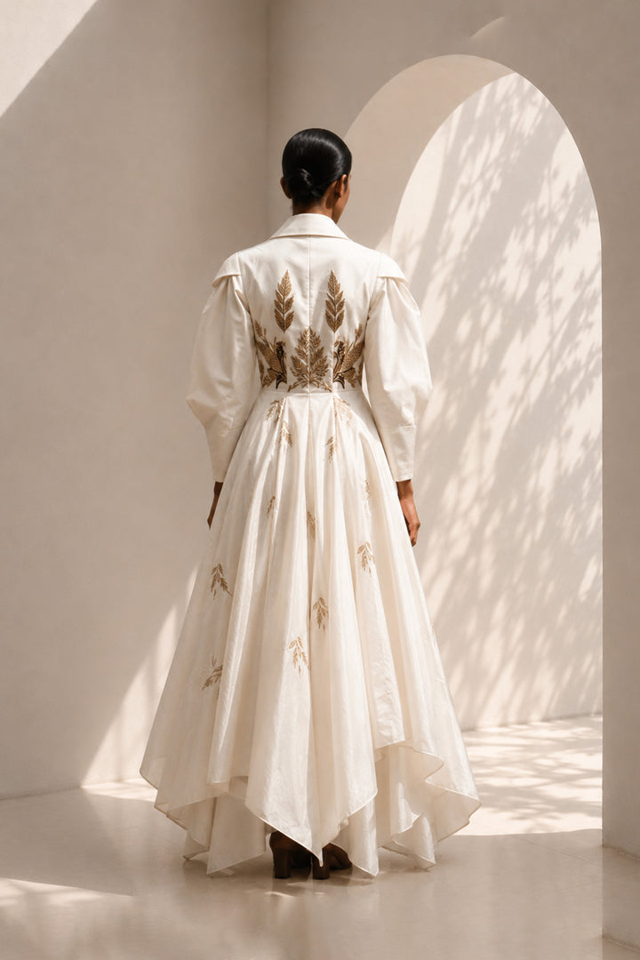 Ivory statement gown featuring sculptural sleeves, delicate embroidery, and an effortlessly flowing silhouette.