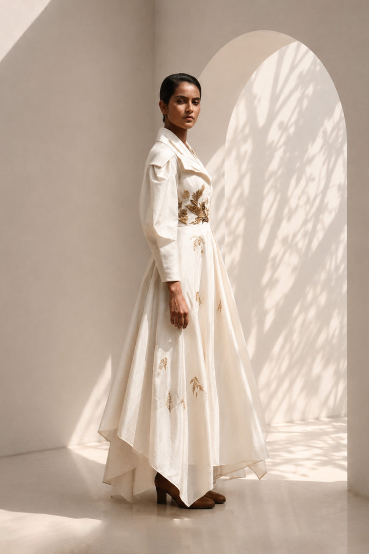 Ivory statement gown featuring sculptural sleeves, delicate embroidery, and an effortlessly flowing silhouette.