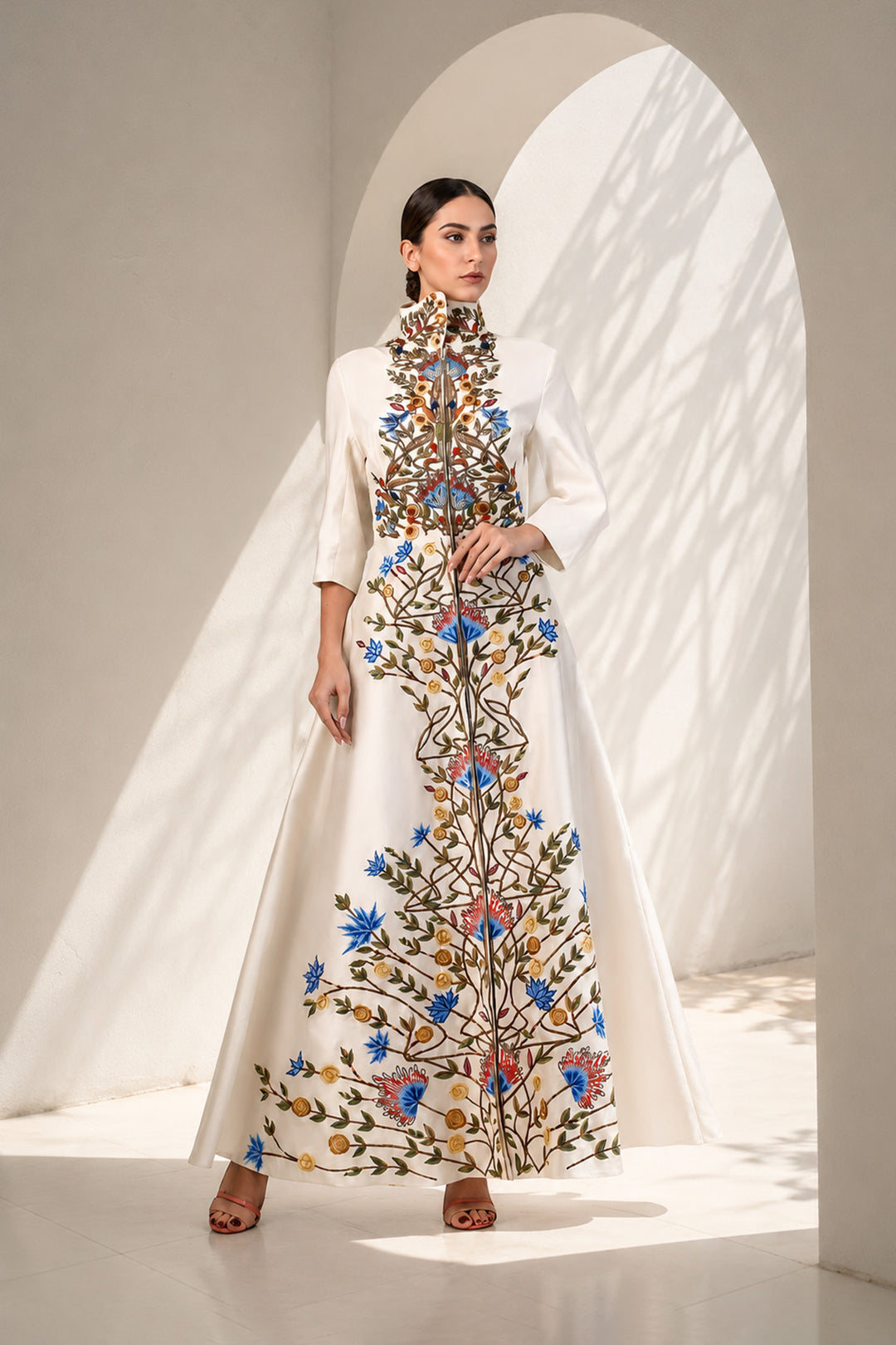 Ivory striking coat gown featuring statement handcrafted embroidery, a sculpted high stand collar with concealed front closure , three-quarter sleeves, &amp; graceful flared silhouette.