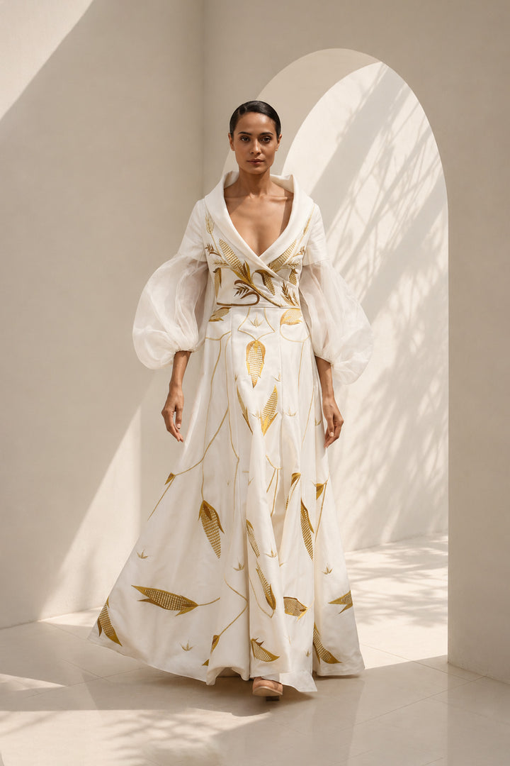 Ivory gown featuring statement sleeves, elegant shwal collar neckline and nature inspired motif embroidery.