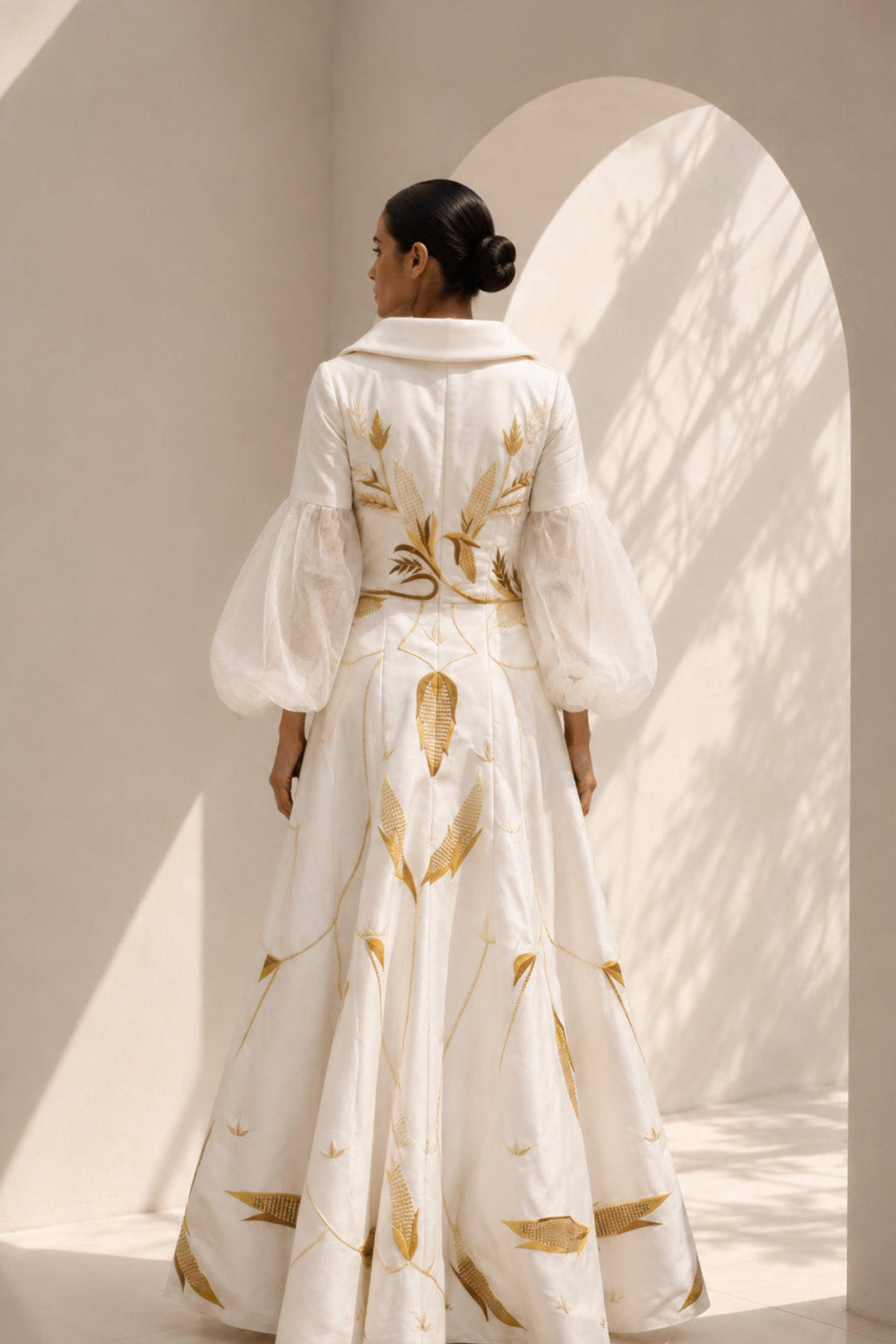 Ivory gown featuring statement sleeves, elegant shwal collar neckline and nature inspired motif embroidery.