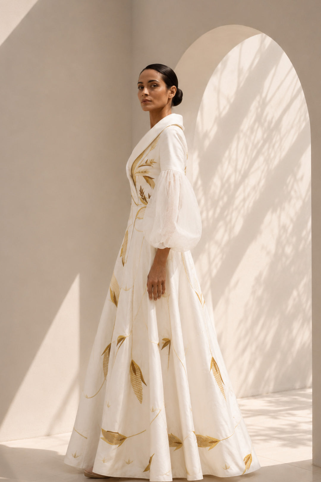 Ivory gown featuring statement sleeves, elegant shwal collar neckline and nature inspired motif embroidery.
