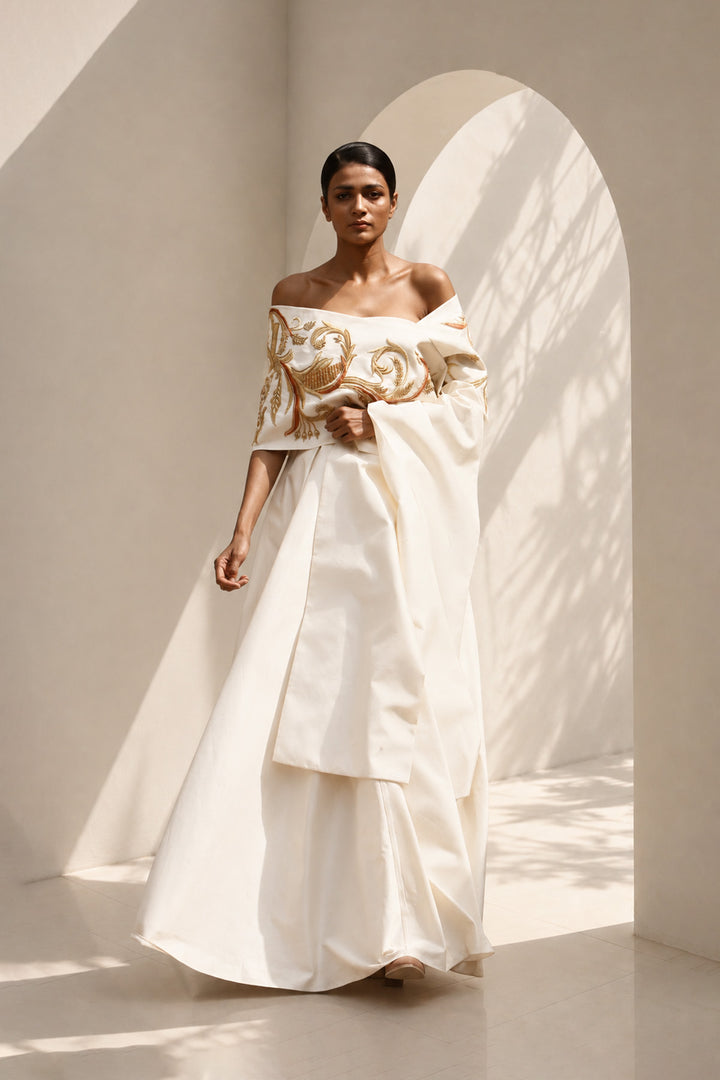 Ivory draped ensemble featuring off-shoulder embroidered stole, sculptural layering.