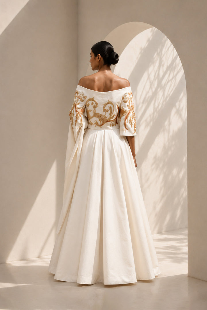 Ivory draped ensemble featuring off-shoulder embroidered stole, sculptural layering.