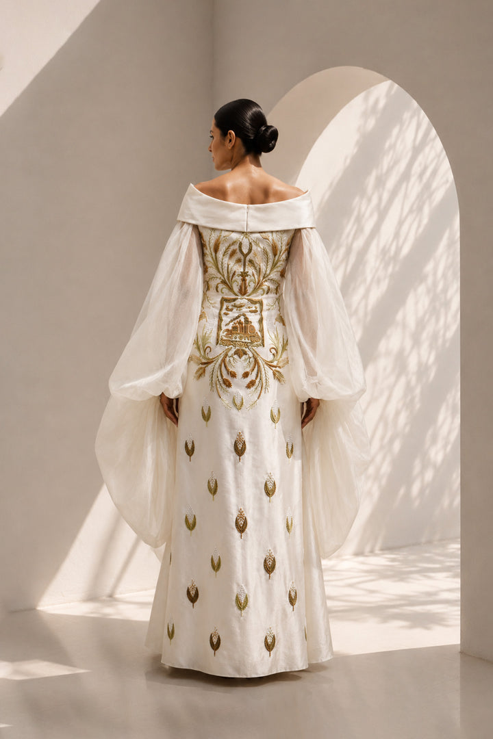 Ivory embroidered column gown featuring an elegant off-shoulder neckline, voluminous sheer sleeves.