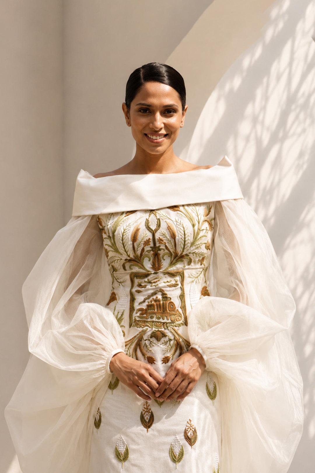 Ivory embroidered column gown featuring an elegant off-shoulder neckline, voluminous sheer sleeves.