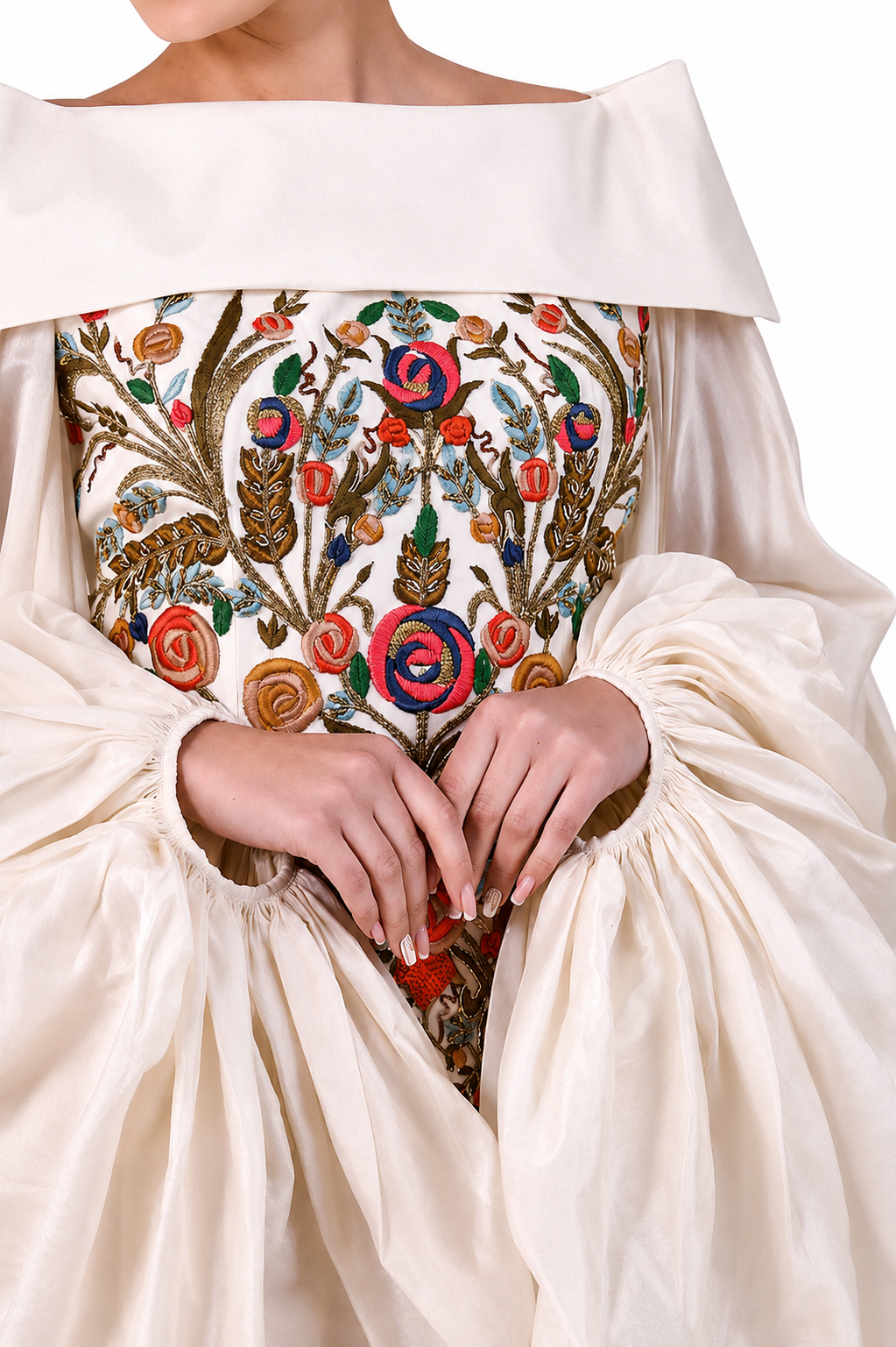 Close-up of a cream-colored dress with intricate floral embroidery on a white background