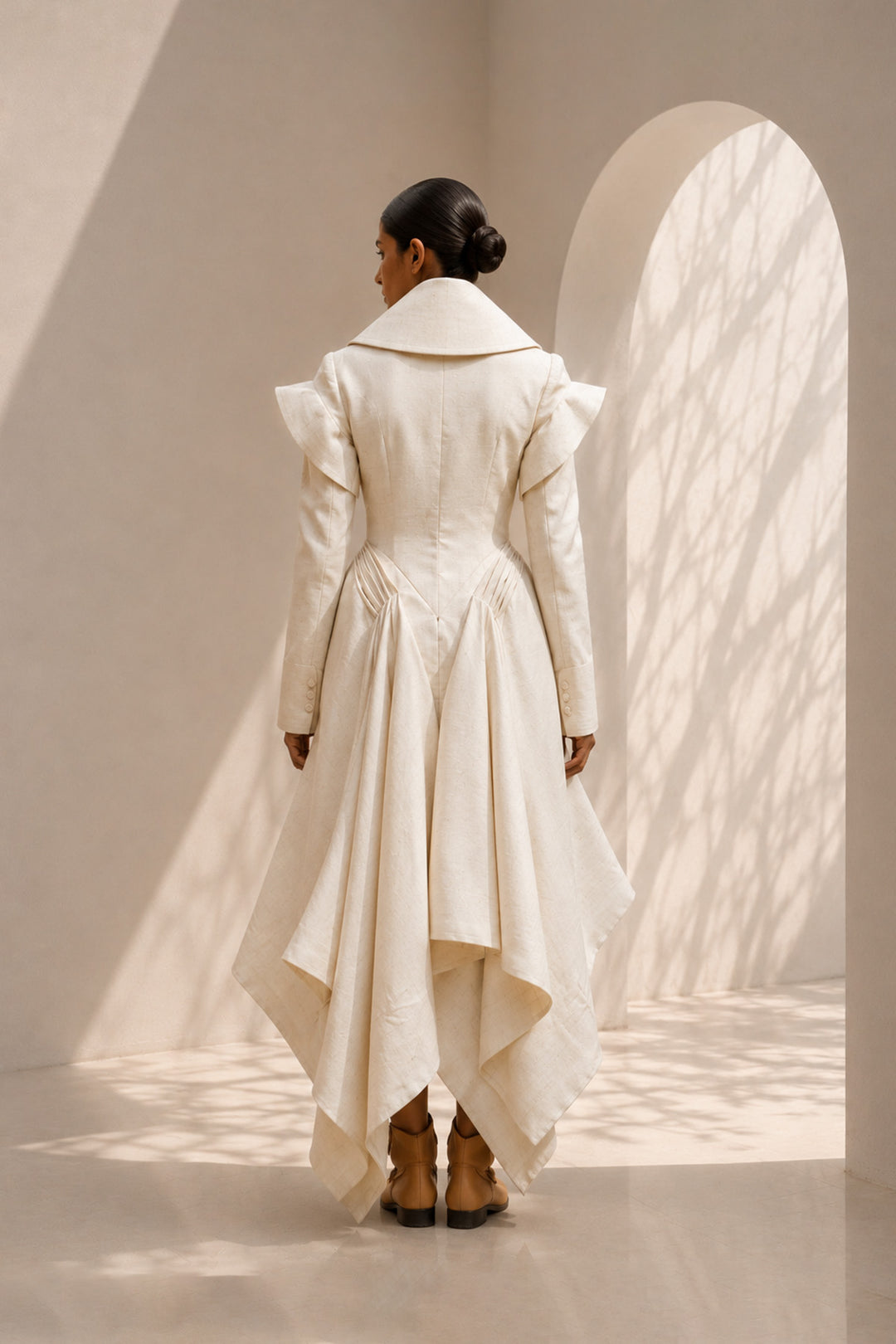 Ivory dress featuring an architectural oversized collar, sculpted shoulders, and fluid draped panels.