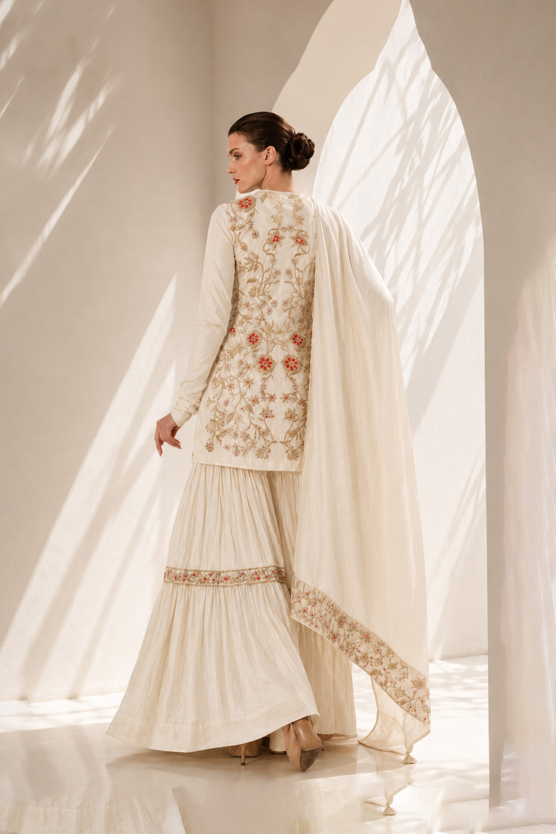 Ivory kurta set adorned with delicate floral embroidery, paired with a tiered sharara and embroidered dupatta.