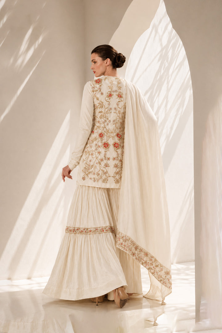 Ivory kurta set adorned with delicate floral embroidery, paired with a tiered sharara and embroidered dupatta.