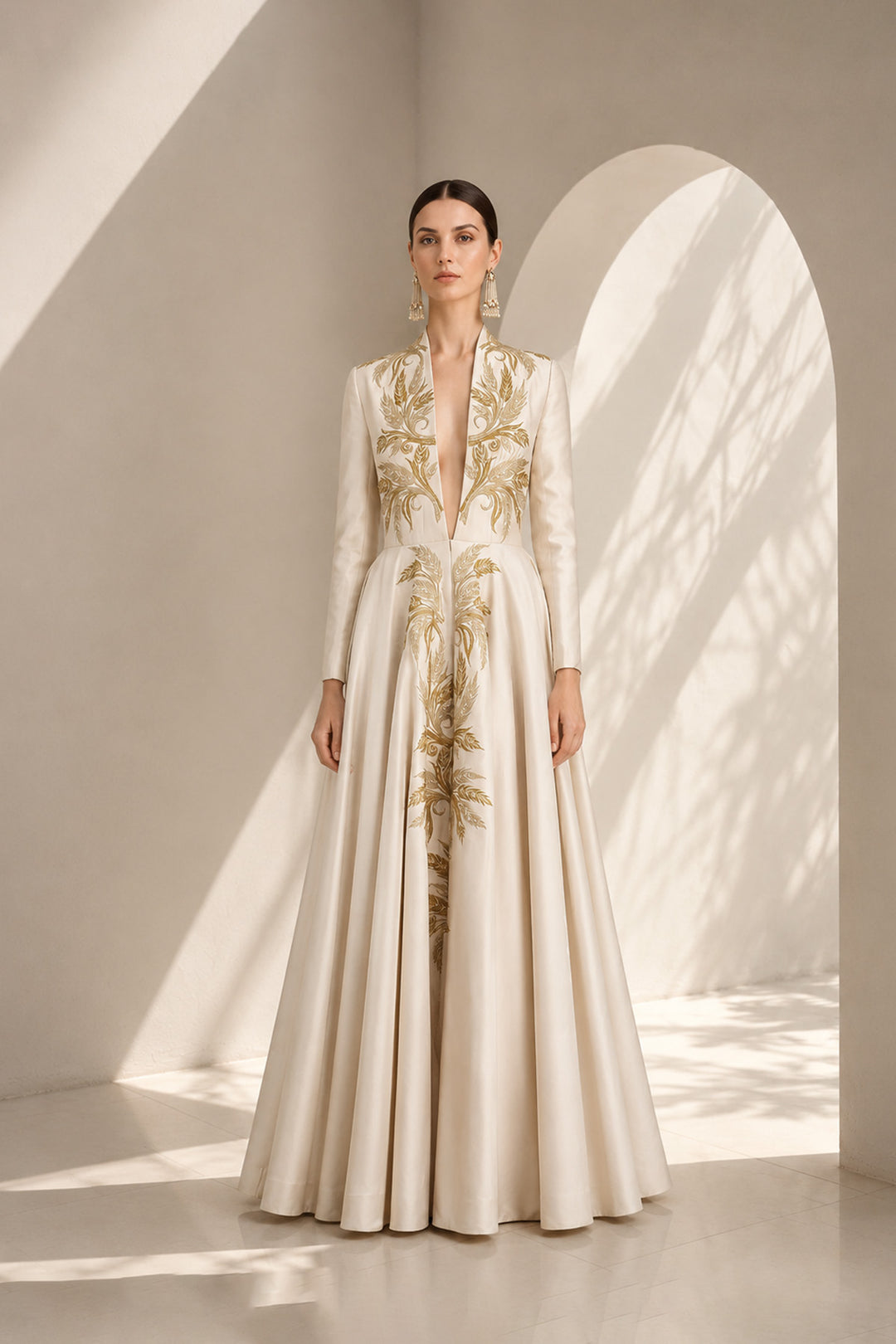 Ivory embroidered gown featuring an architectural plunging neckline, full-sleeved, structured bodice, voluminous flared hem.