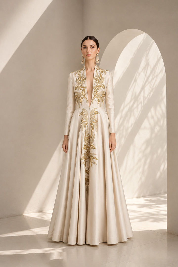 Ivory embroidered gown featuring an architectural plunging neckline, full-sleeved, structured bodice, voluminous flared hem.