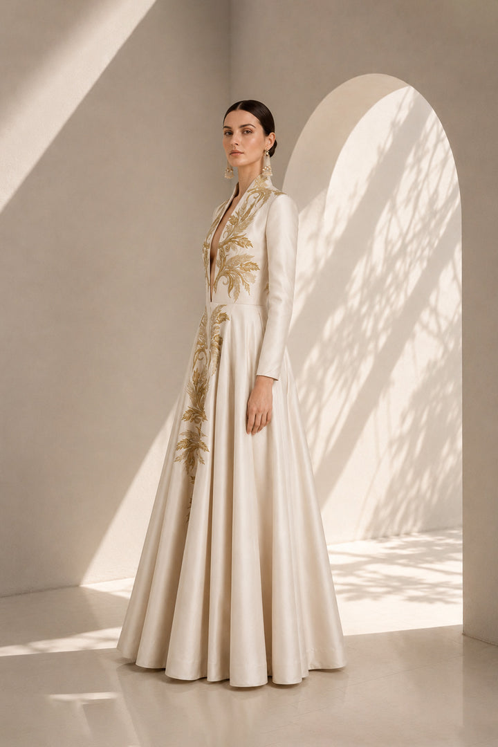 Ivory embroidered gown featuring an architectural plunging neckline, full-sleeved, structured bodice, voluminous flared hem.