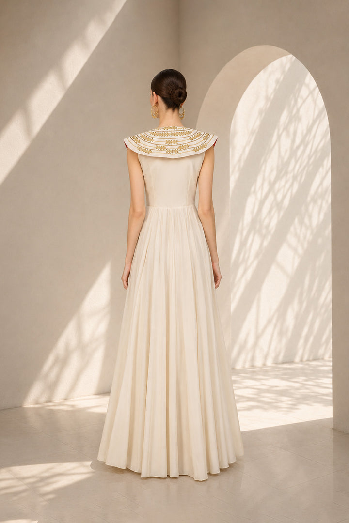 Ivory floor-length gown adorned with intricate embroidery, sculptural cape collar,vertical embroidered front panel for an elongated look.