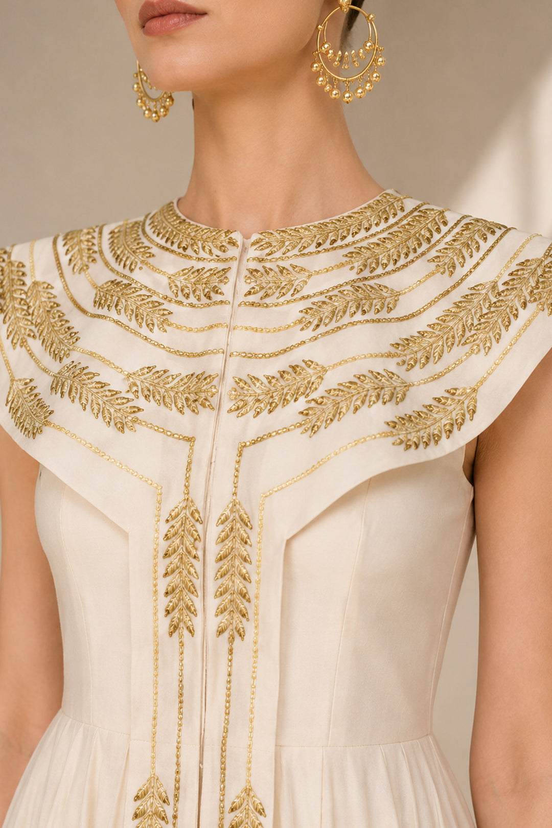 Ivory floor-length gown adorned with intricate embroidery, sculptural cape collar,vertical embroidered front panel for an elongated look.