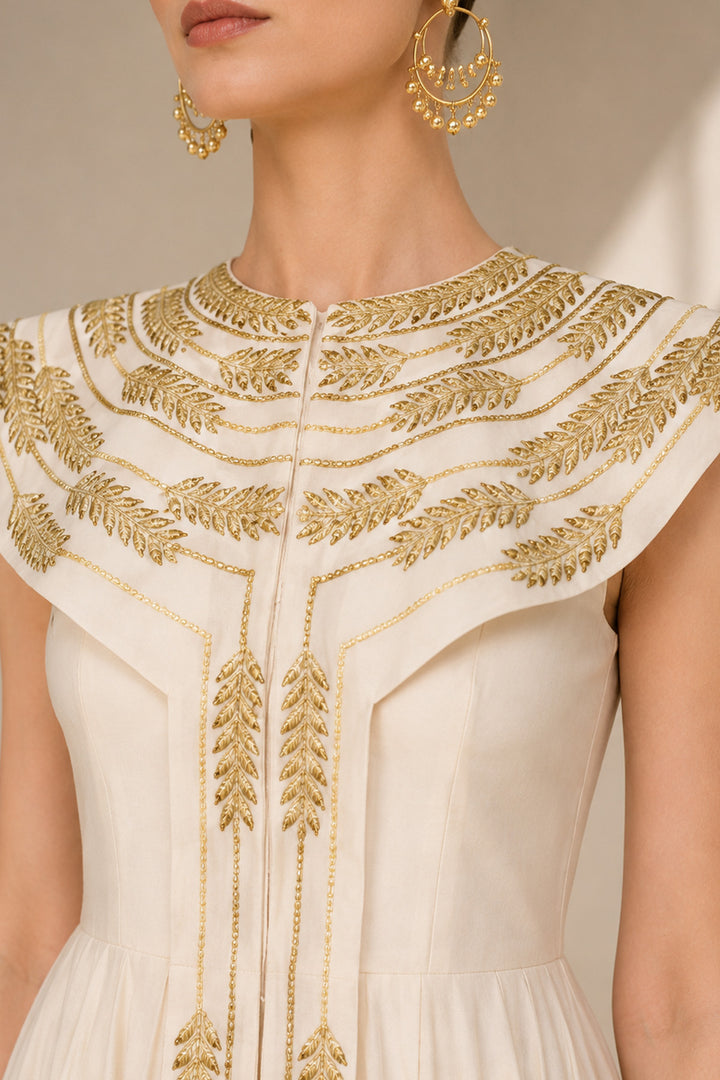 Ivory floor-length gown adorned with intricate embroidery, sculptural cape collar,vertical embroidered front panel for an elongated look.