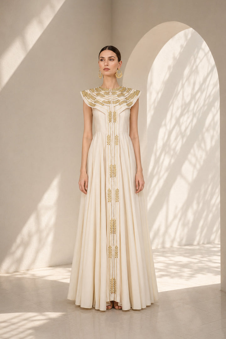 Ivory floor-length gown adorned with intricate embroidery, sculptural cape collar,vertical embroidered front panel for an elongated look.
