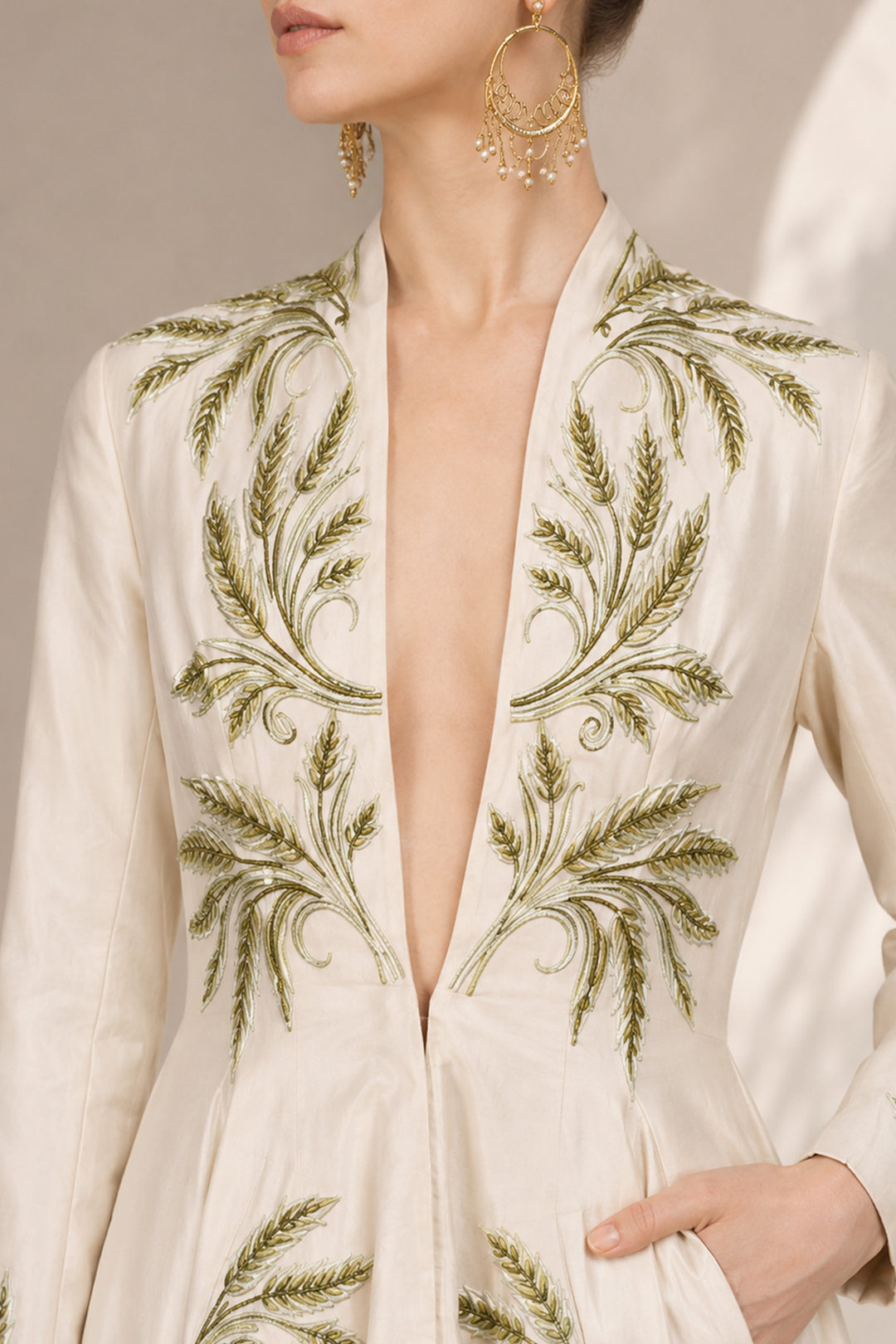 Ivory embroidered gown featuring a dramatic deep V-neckline, full-sleeves with embroidered cuffs, concealed side pockets.
