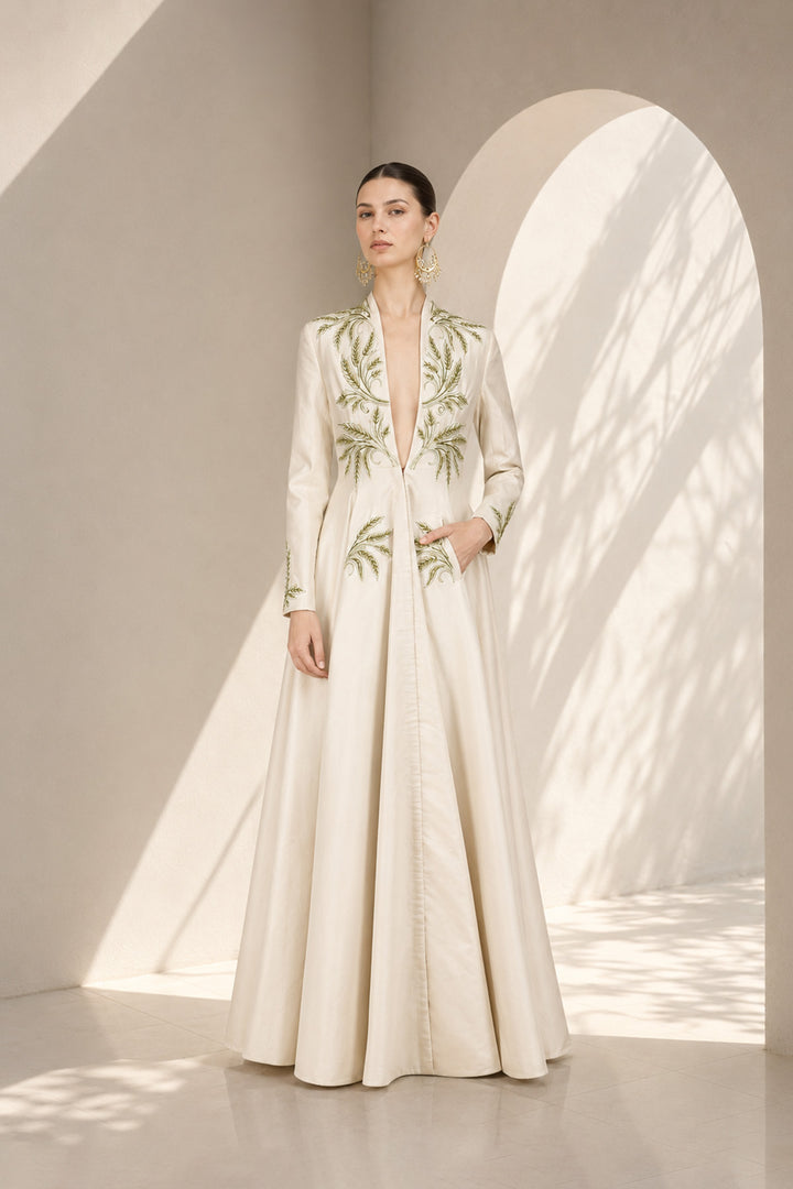 Ivory embroidered gown featuring a dramatic deep V-neckline, full-sleeves with embroidered cuffs, concealed side pockets.