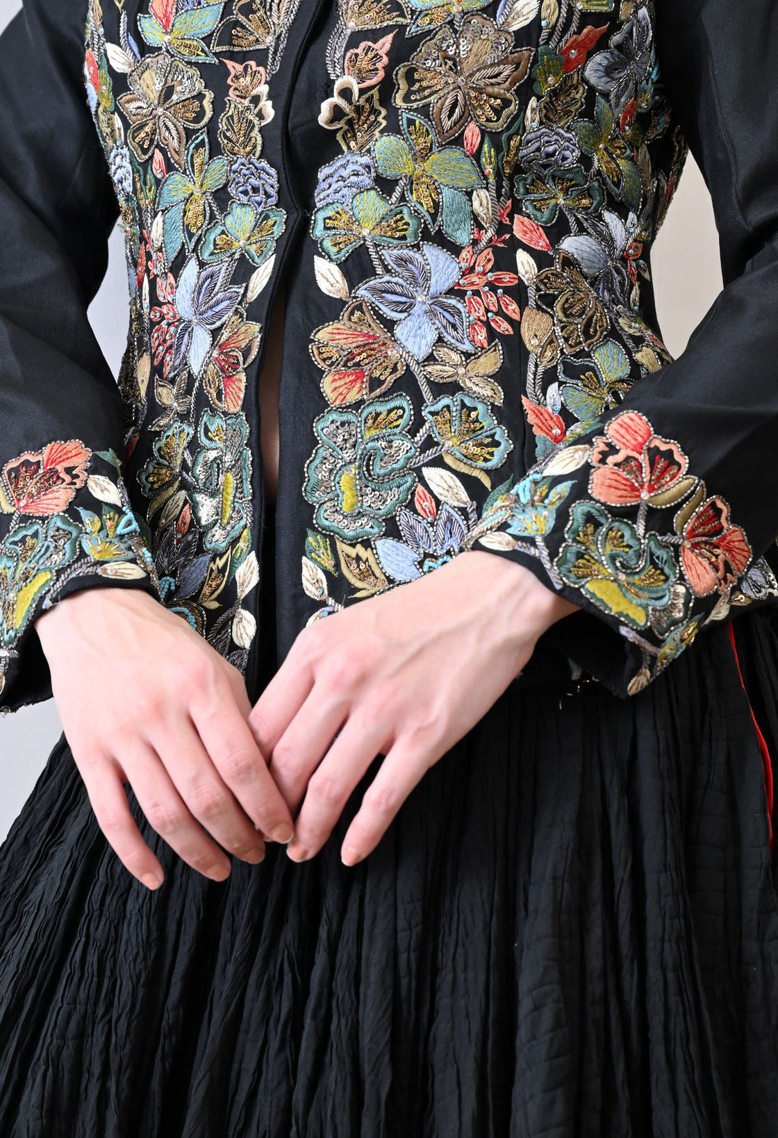 A black jacket features intricate all-over embroidery with skirt