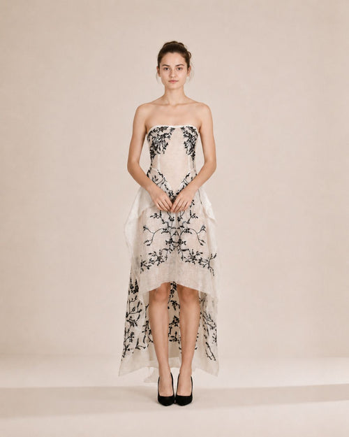 Woman wearing a strapless floral dress on a plain background