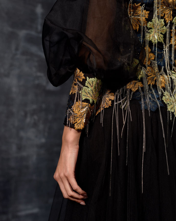 A elegant black off-shoulder gown features a dramatic sleeve top.