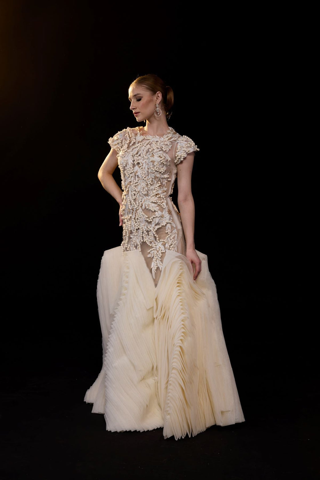 A elegant gown features a sheer, cap-sleeve bodice adorned with intricate 3D floral embellishment.