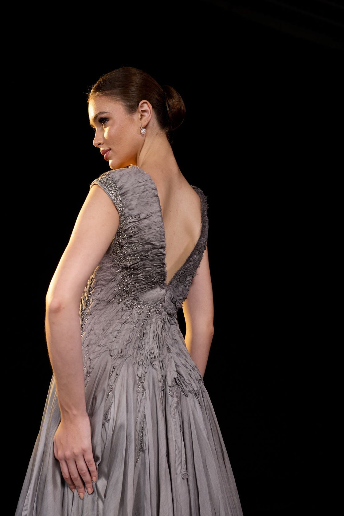 A striking grey gown features a deep V-neckline and delicately ruched bodice.