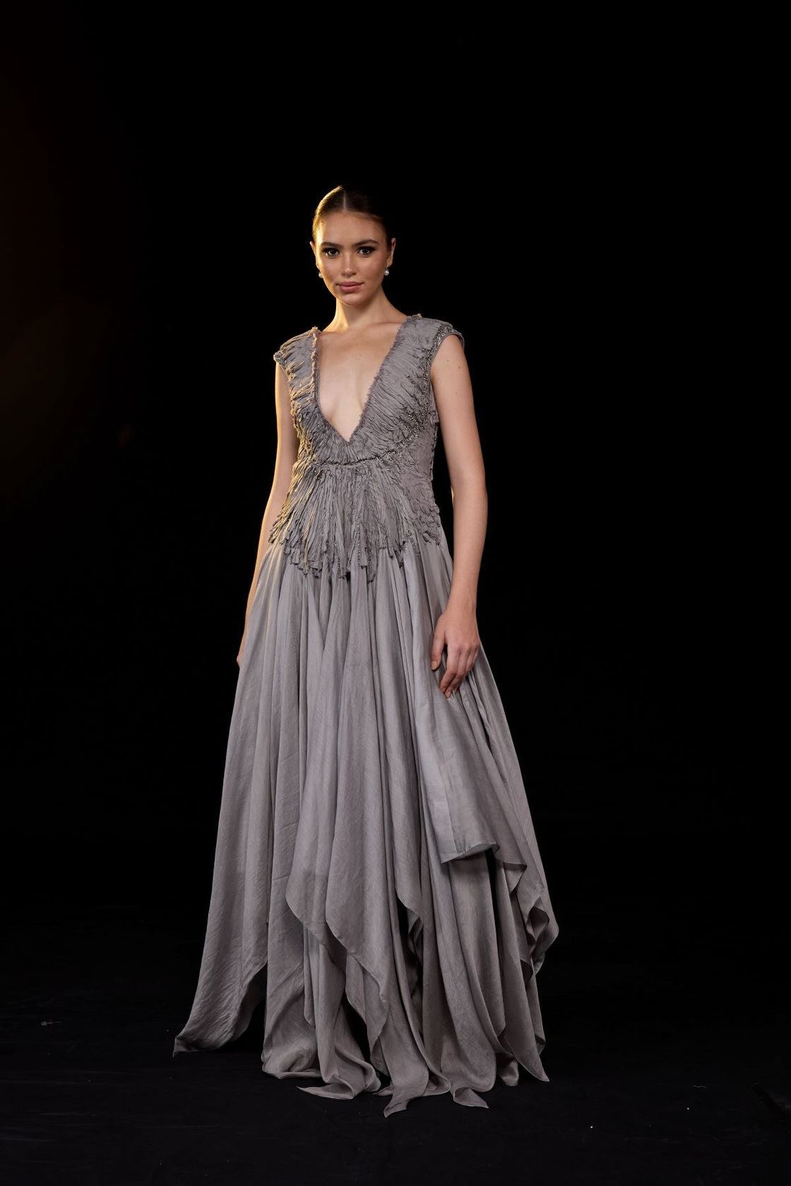 A striking grey gown features a deep V-neckline and delicately ruched bodice.