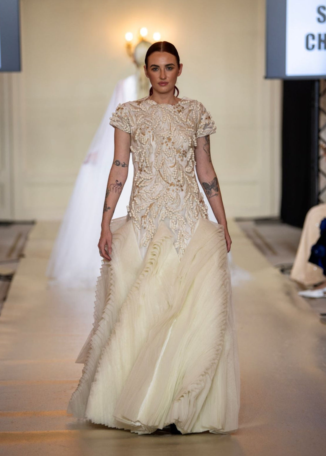 A exquisite gown features a sculpted bodice with ornate bead and thread embroidery