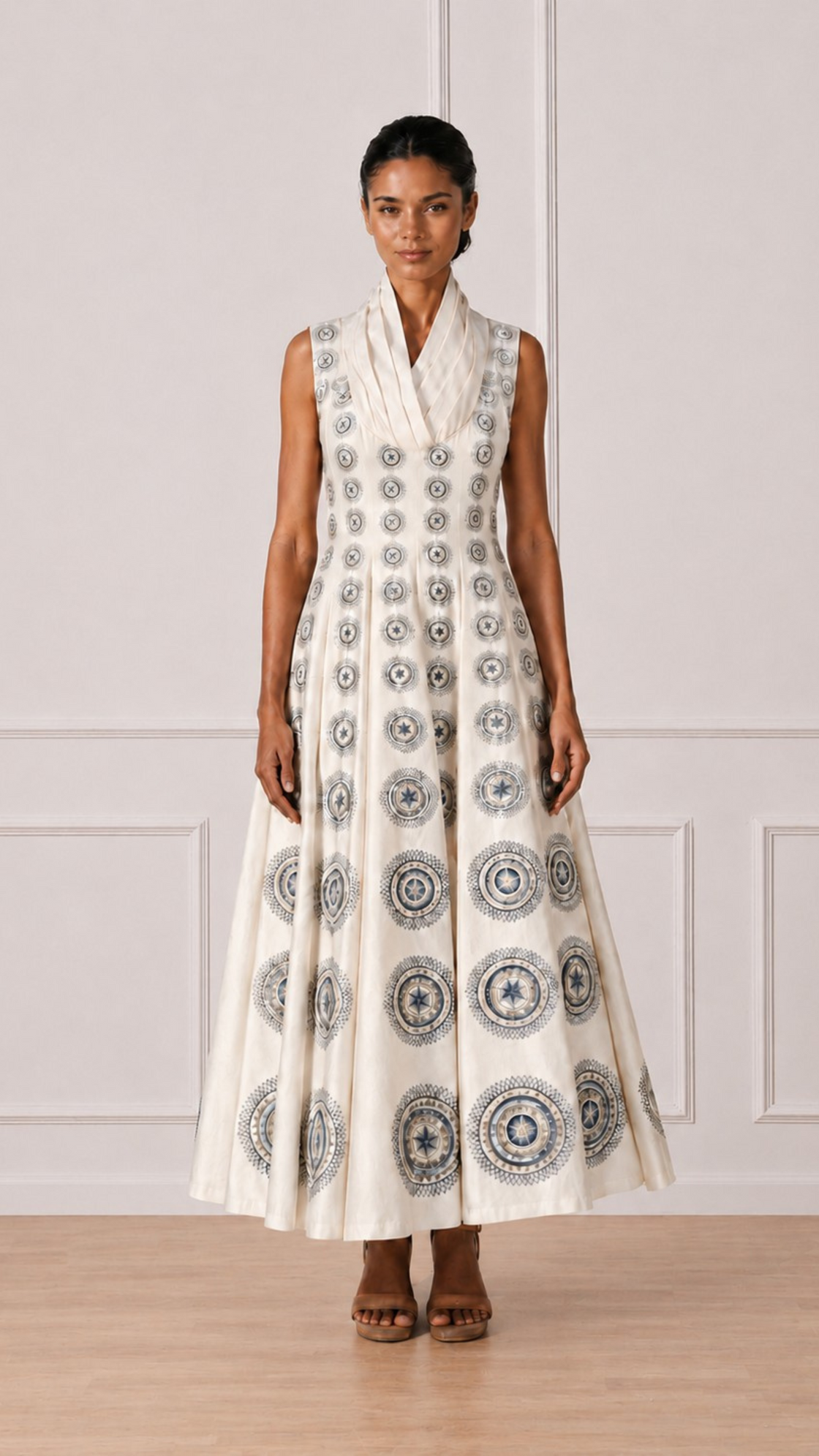 Woman wearing a sleeveless dress with a geometric pattern against a white paneled wall.