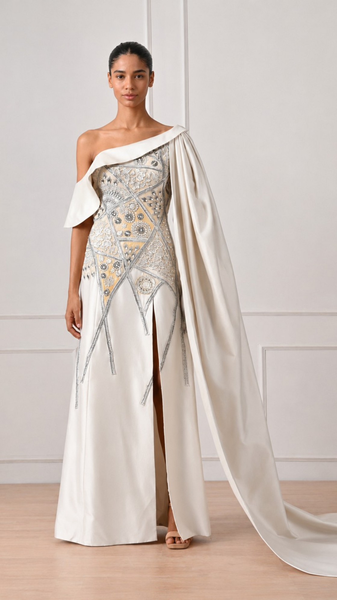 Woman wearing a white evening gown with a long train against a plain background