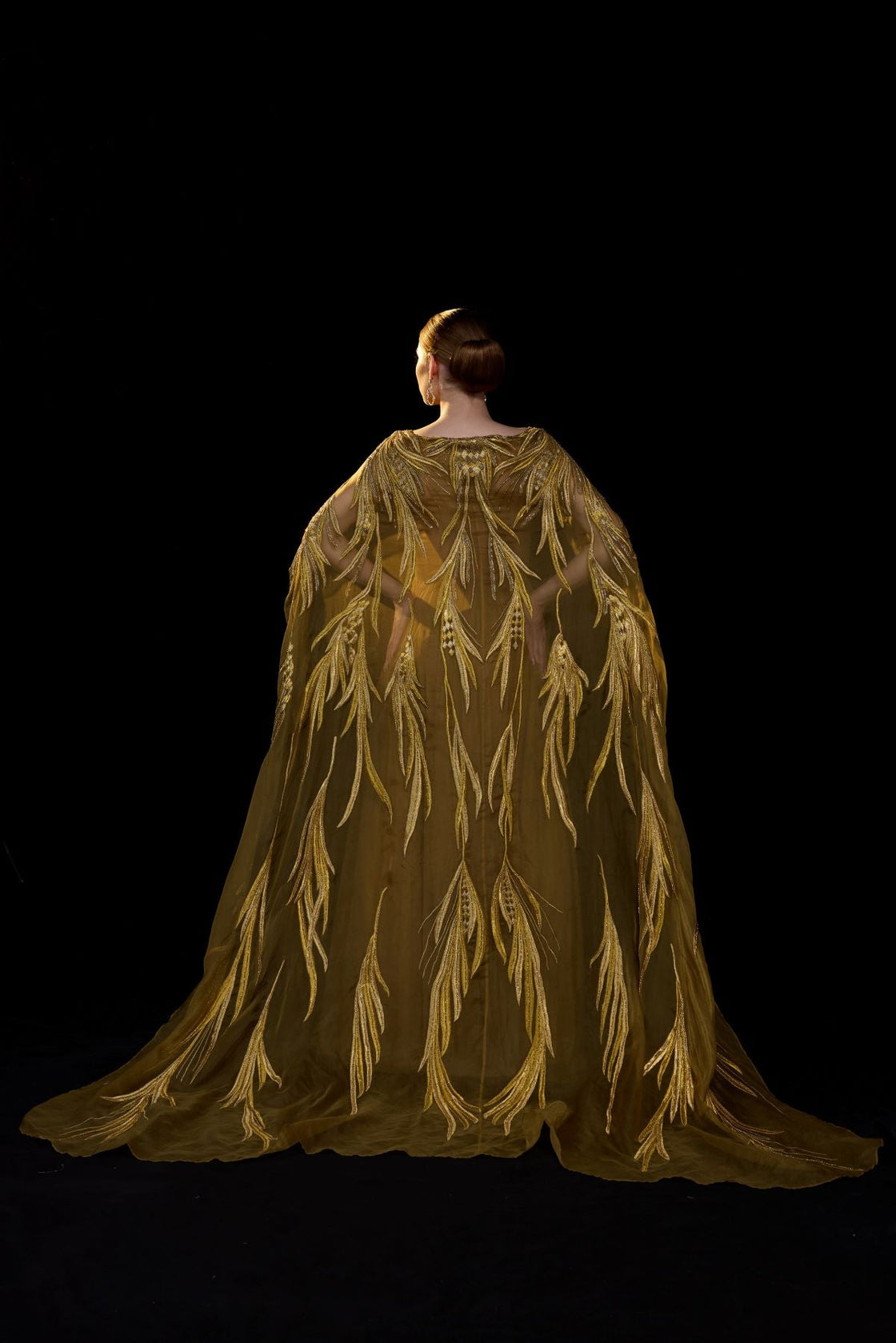 Golden-bronze embroidered gown with elegant, flowing cape sleeves.
