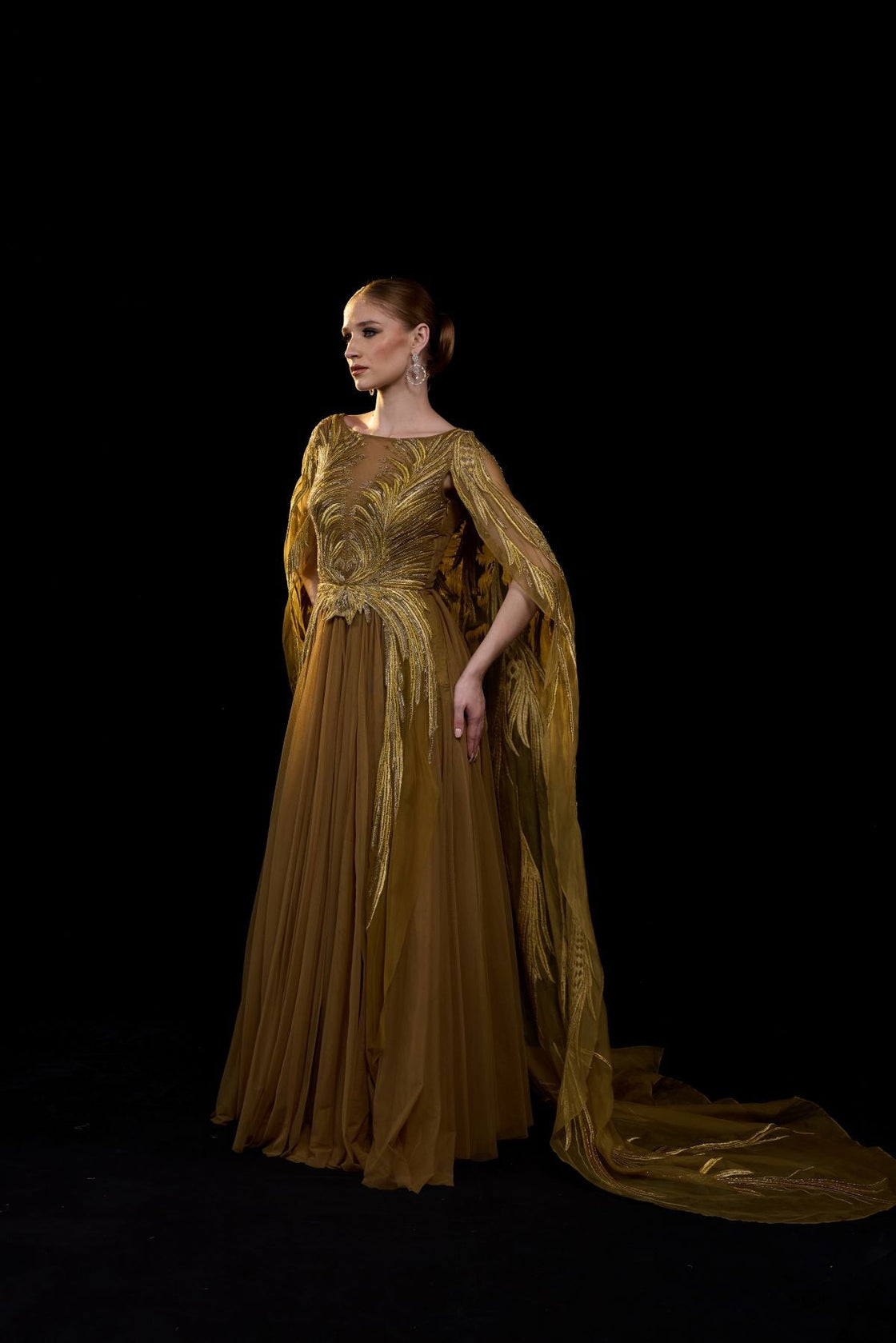 Golden-bronze embroidered gown with elegant, flowing cape sleeves.