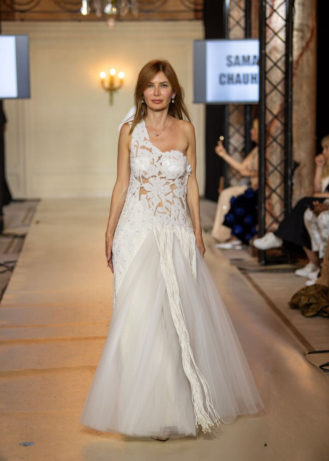 This one-shoulder ivory gown features intricate floral appliqué with sheer paneling
