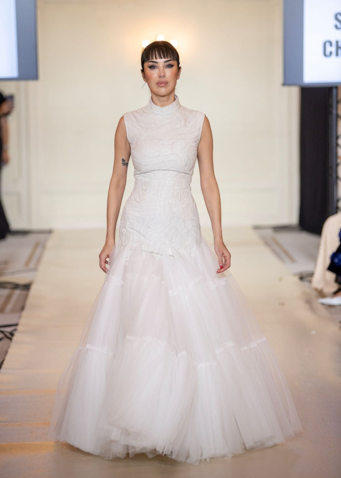 A elegant sleeveless gown features a high neckline and a fitted