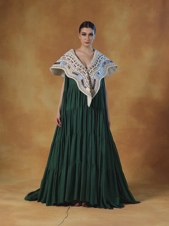 Floor Length Cotton Tier Dress In Olive Green. It Is Topped With A Heavy Embroidered Cape Around The Neckline And Shoulders.