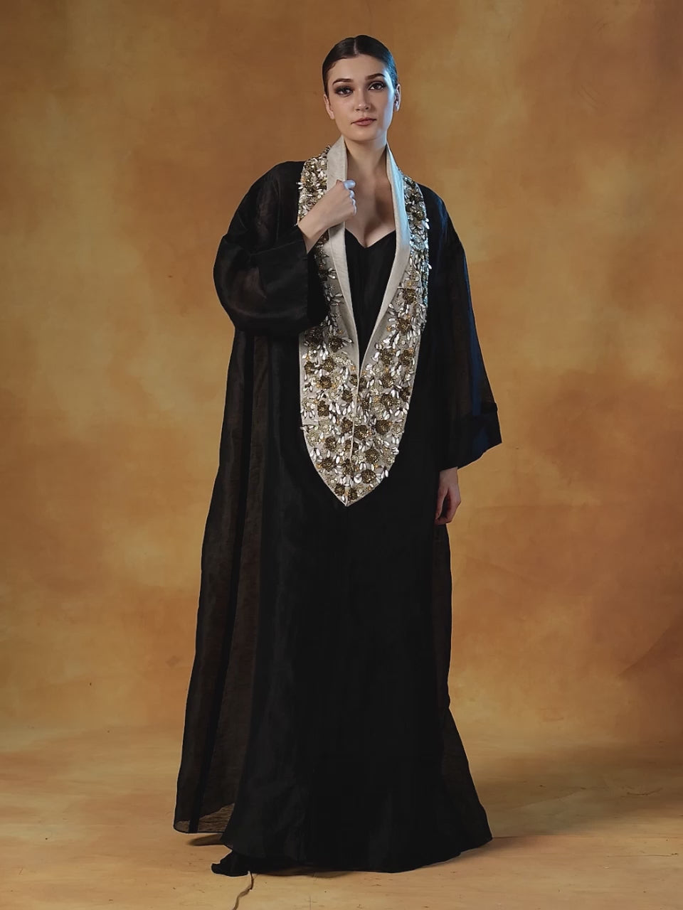 A black floor length lose-fitted gown with an embellished deep yoke neck line.