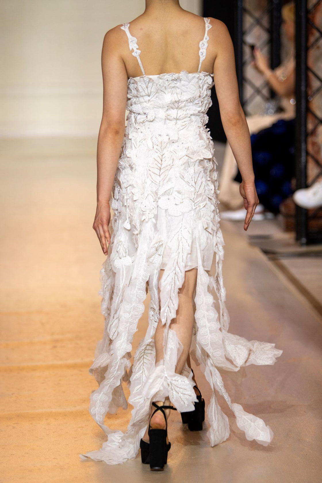 Turn heads in this strappy white gown featuring delicate 3D floral appliqués