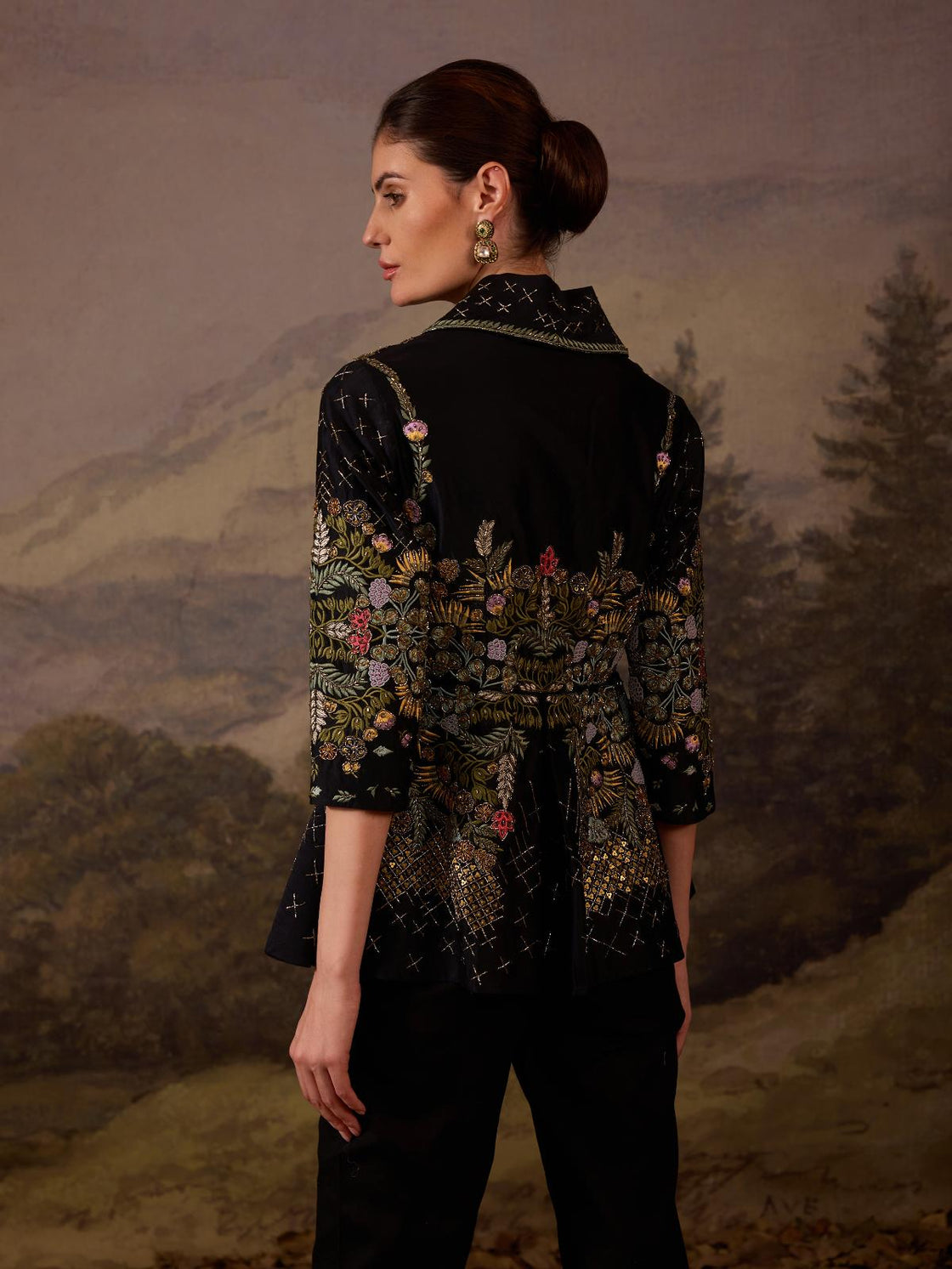 A black jacket features intricate all-over embroidery with slim pants