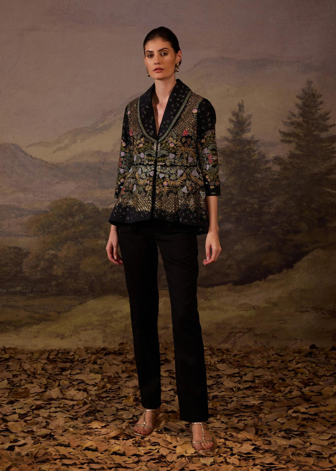 A black jacket features intricate all-over embroidery with slim pants