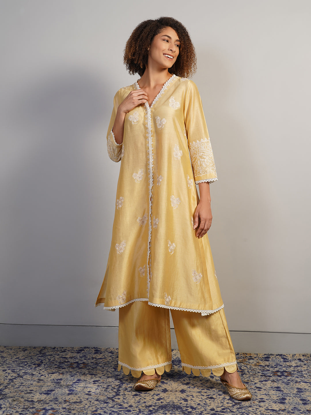 A pleasant, V-neck beige cotton silk suit set that is adorned with subtle aari work embroidery
